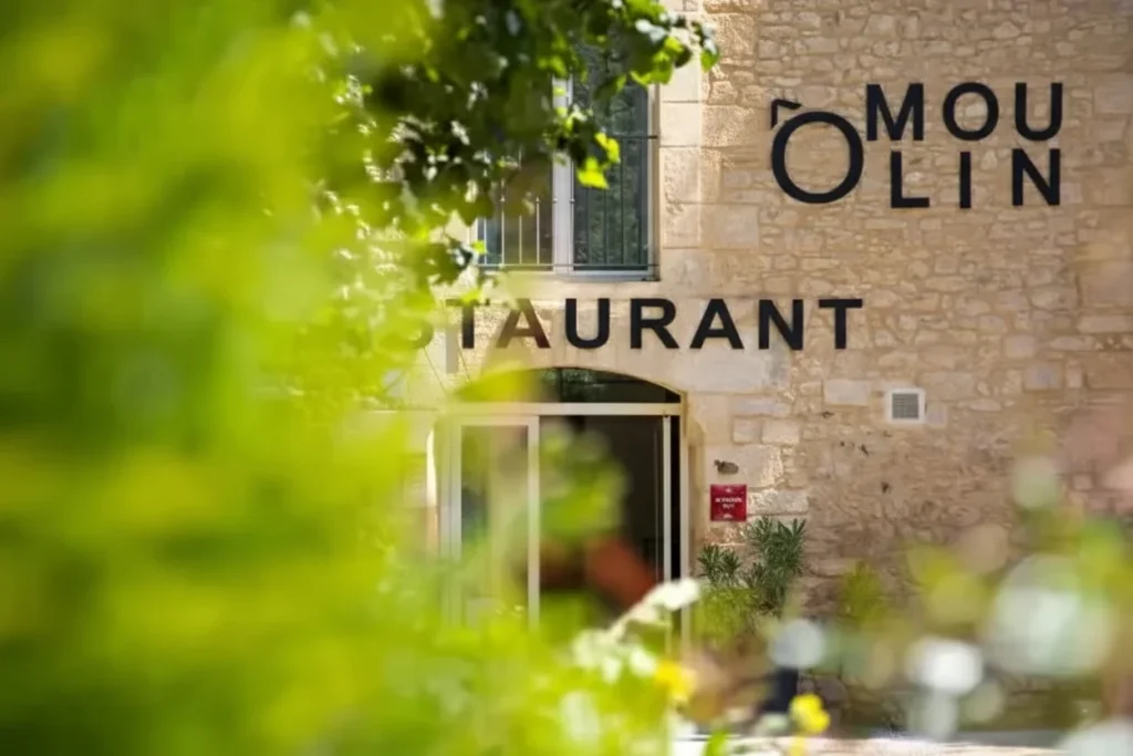 Exterior photo of the stone building entrance for Ô Moulin restaurant in Carsac-Aillac, highlighting the charming ambiance and location as one of the best restaurants in Domme.