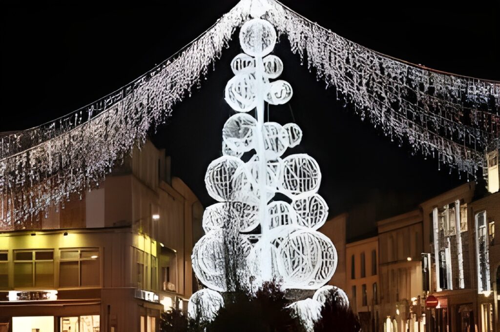 A beautifully decorated Christmas tree stands prominently in the Bergerac Christmas Market, one of the Christmas Markets in Dordogne, surrounded by festive city lights.