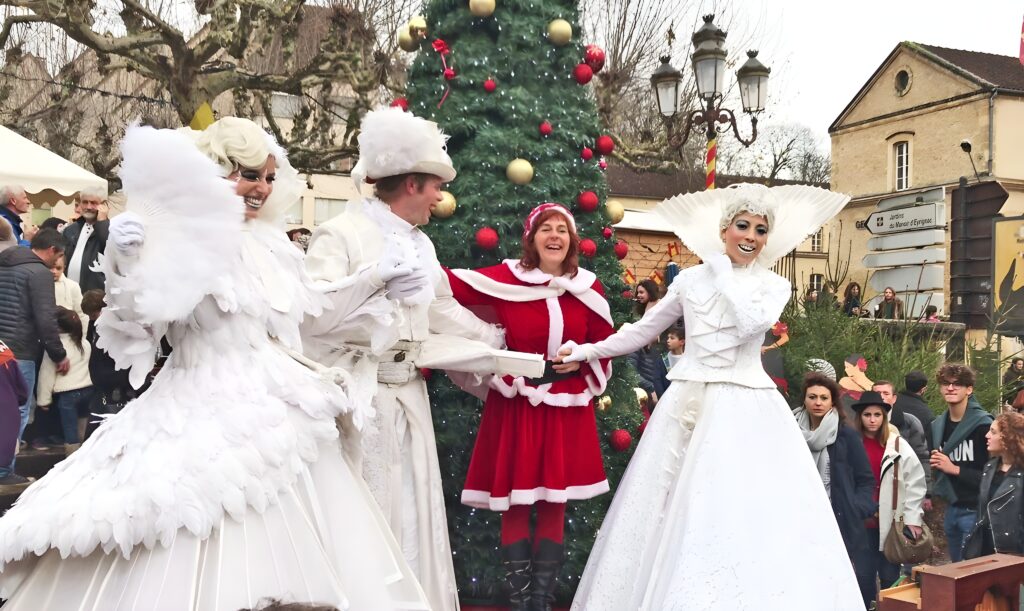 Three people adorned in white and red costumes, celebrating the festive atmosphere of the Sarlat Christmas Market.