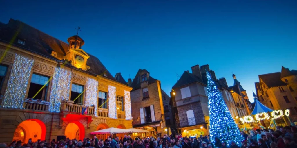 A medieval French town square in Dordogne lit up at night for Christmas, one of the must-see activities in Dordogne.