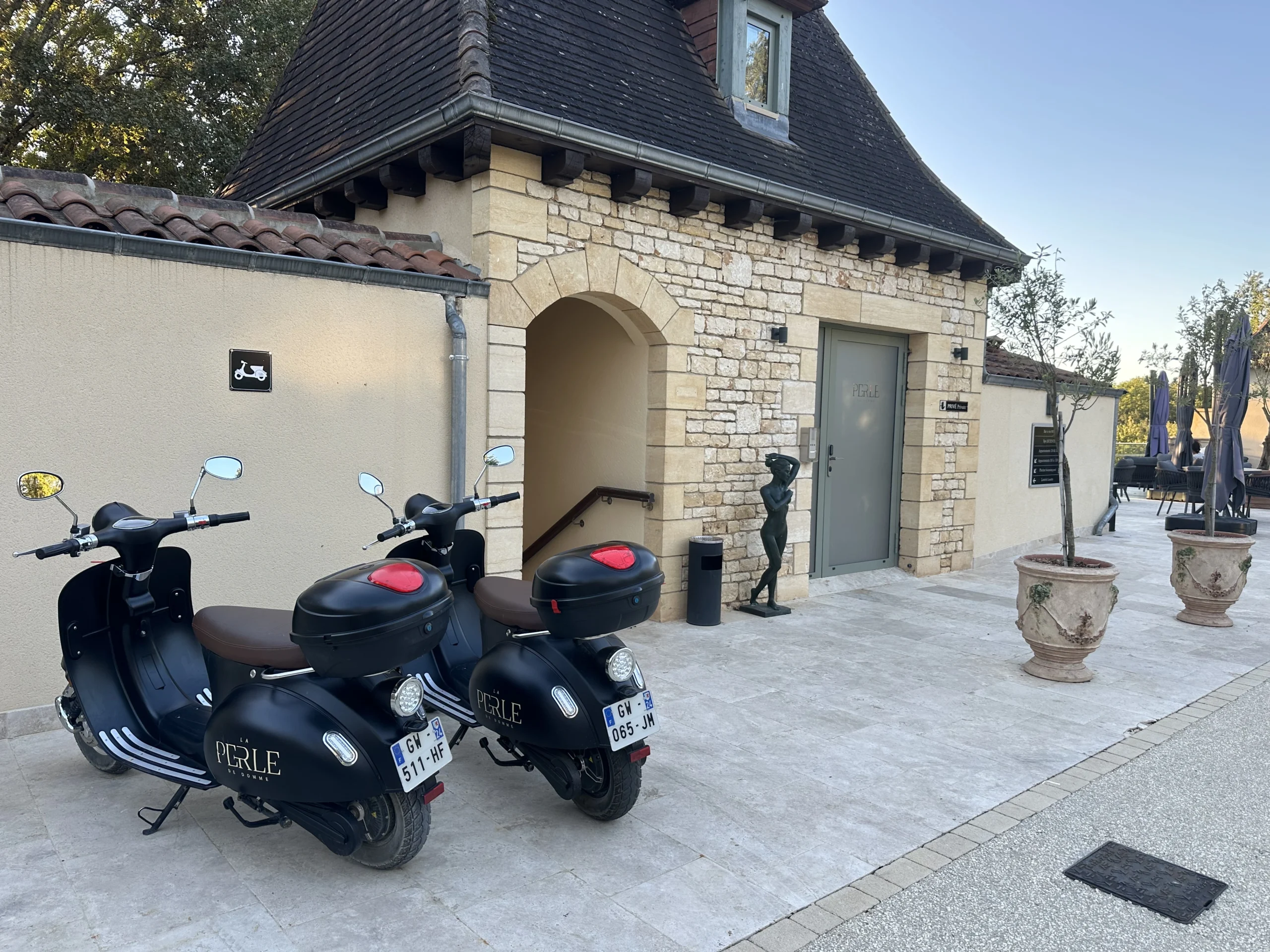 Two motor scooters parked in front of a stone building in Dordogne, near La Perle de Domme.